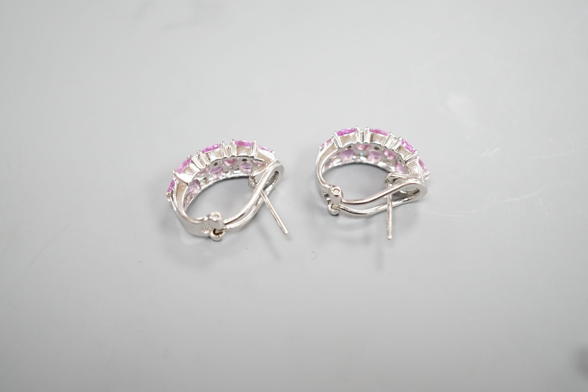 A modern pair of 14k white metal, pink sapphire and diamond cluster set half hoop earrings, 17mm, gross weight 8.3 grams.